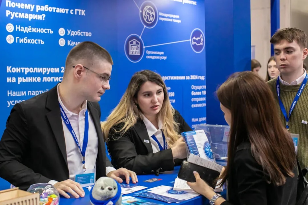 Business professionals networking at a logistics and transport exhibition. Corporate representatives discuss logistics solutions and services at a TRST Expo booth. A modern B2B trade show environment focused on supply chain innovation.